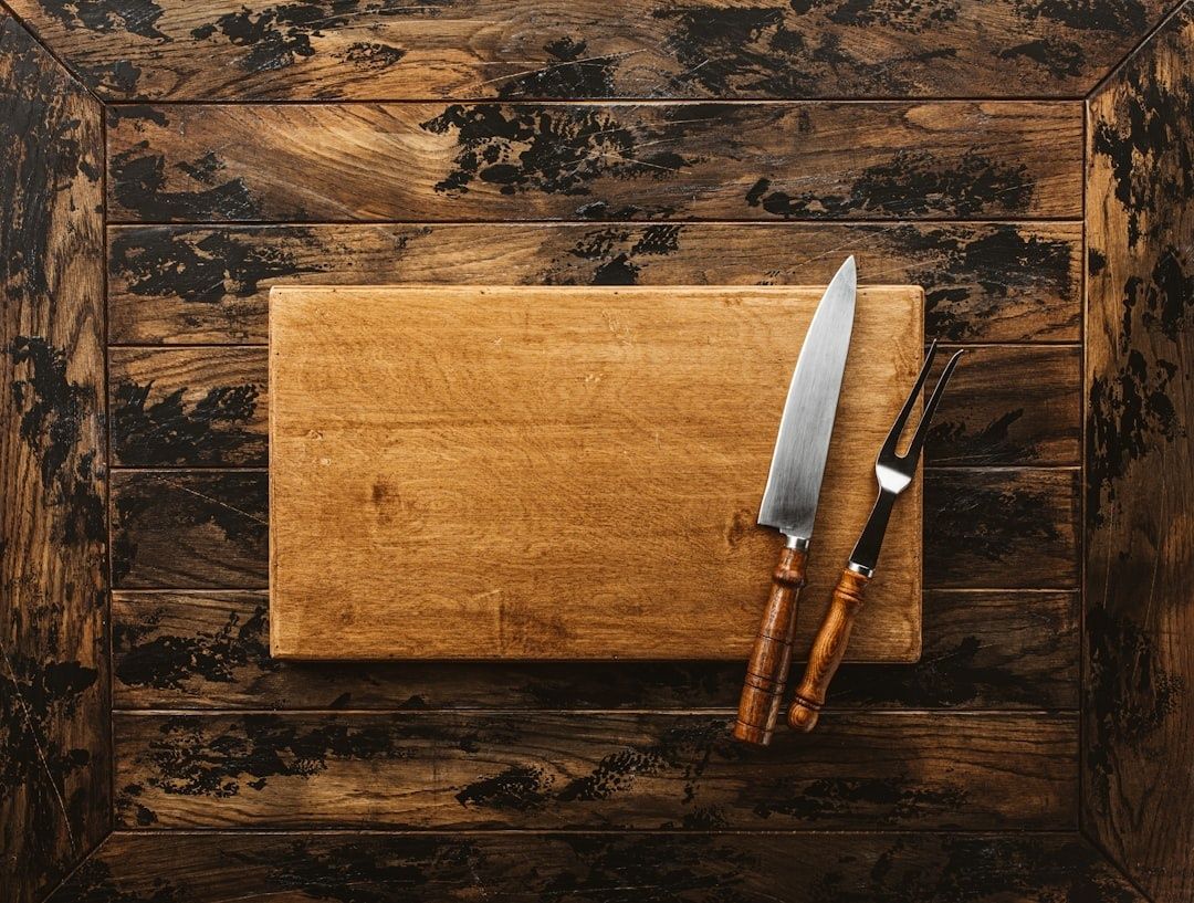 Träskärbräda med kockkniv och gaffel på ett rustikt träbord